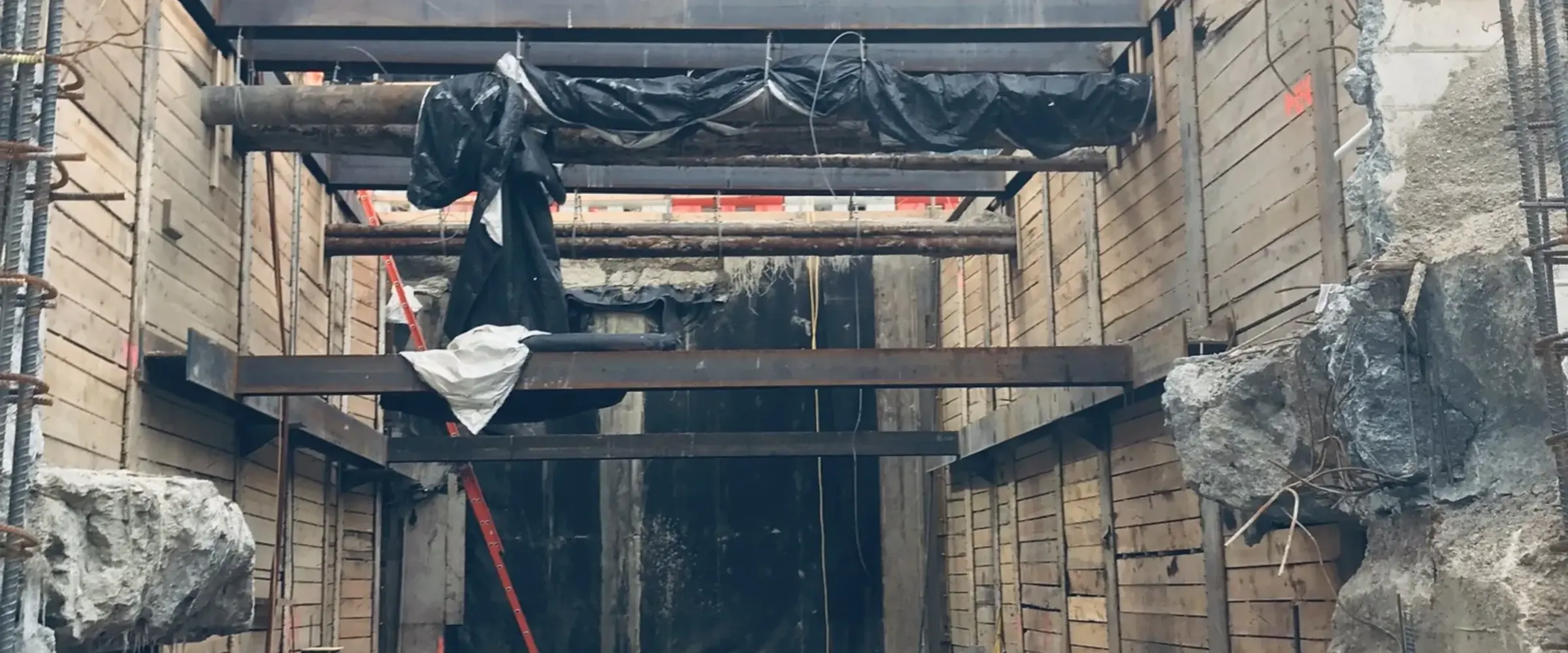 Deep shored excavation with a reinforcing mat beside a glass tower