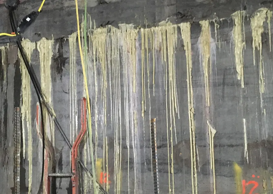 Foundation wall with injection ports and cured grout runs